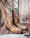 Side view of the Luminous Petal Corral Boots with a wood backdrop.