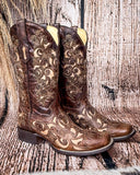 Side view of the Desert Blossom Corral Boots with a wood backdrop.