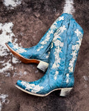 The Navy Blossom Corral Boots displayed on cowhide.