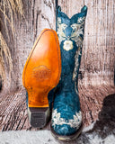 Front and bottom view of the Navy Blossom Corral Boots with a wood backdrop,