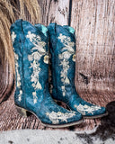 Side view of the Navy Blossom Corral Boots with a wood backdrop.