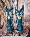 Back view of the Navy Blossom Corral Boots with a wood backdrop.