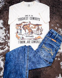Flat lay of a pair of Cowgirl Tuff Jeans and the Toughest Cowgirls Graphic Tee laying on cowhide.