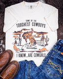 Styled flat lay of the Toughest Cowgirls Graphic Tee laying on cowhide.