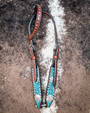 The Turquoise Wash Bull Coin Single Ear Headstall displayed on cowhide.