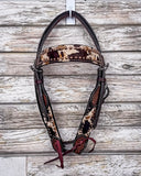 A zoom in of the Peppered Hair On Hide Browband Headstall displayed on a wood backdrop.