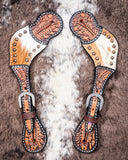 Cowhide and Brass Accent Ladies Spur Straps displayed on cowhide.