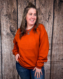 Model wearing the Pumpkin Spice Pullover in front of a wood backdrop.