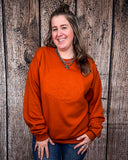 Model wearing the Pumpkin Spice Pullover in front of a wood backdrop.
