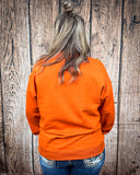 Back view of a model wearing the Pumpkin Spice Pullover in front of a wood backdrop.