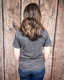 The Branded Pony Graphic Tee modeled and styled In front of a wood backdrop.