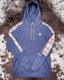 The Canyon Ladies Hooey Hoodie in Blue with Aztec on sleeves being displayed on cowhide.