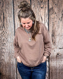 The Stillwater Tunic Top styled and modeled on a women in front of wood backdrop.