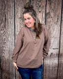 The Stillwater Tunic Top styled and modeled on a women in front of wood backdrop.