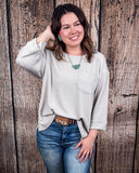 The Ellis Top in Pearl Grey being styled and modeled on women in front of wood background.