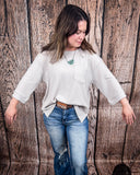 The Ellis Top in Pearl Grey being styled and modeled on women in front of wood background.