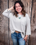 The Ellis Top in Pearl Grey being styled and modeled on women in front of wood background.