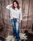 The Ellis Top in Pearl Grey being styled and modeled on women in front of wood background.