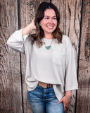 The Ellis Top in Pearl Grey being styled and modeled on women in front of wood background.