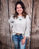 The Ellis Top in Pearl Grey being styled and modeled on women in front of wood background.