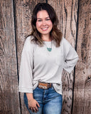 The Ellis Top in Pearl Grey being styled and modeled on women in front of wood background.