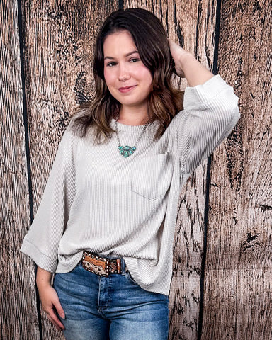 The Ellis Top in Pearl Grey being styled and modeled on women in front of wood background.