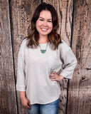 The Ellis Top in Pearl Grey being styled and modeled on women in front of wood background.
