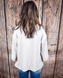 The Ellis Top in Pearl Grey being styled and modeled on women in front of wood background.