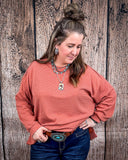 The Stillwater Tunic Top in color Rust being styled and modeled on women in front of wood backdrop.