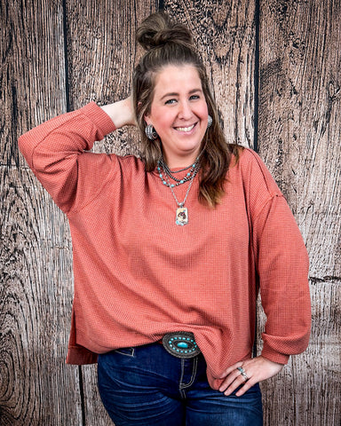 The Stillwater Tunic Top in color Rust being styled and modeled on women in front of wood backdrop.