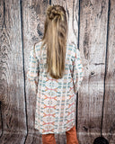 Acoma Aztec Duster from the back being styles and worn by a women in front if wood background.