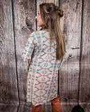 Acoma Aztec Duster from the back being styles and worn by a women in front if wood background.