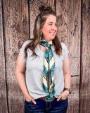 The Sloan Top in Pearl Grey being styled and modeled on a women in front of wood background.