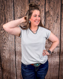 The Sloan Top in Pearl Grey being styled and modeled on a women in front of wood background.