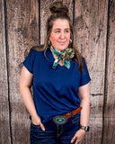 The Thatcher Top in navy being styled and modeled on a women in front of wood background.