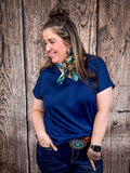 The Thatcher Top in navy being styled and modeled on a women in front of wood background.
