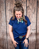 The Thatcher Top in navy being styled and modeled on a women in front of wood background.