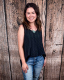 The Caldera Tank in Black being styled with jeans and modeled by a women in front of wood backdrop.