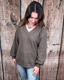 The Hadley Top in mocha being styled with jeans and worn by a women in front of wood background.