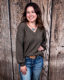 The Hadley Top in mocha being styled with jeans and worn by a women in front of wood background.