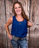 The Caldera Tank in Navy being styled and worn by a women in front of wood background.