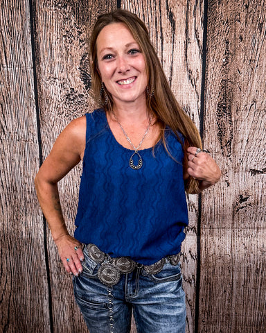 The Caldera Tank in Navy being styled and worn by a women in front of wood background.