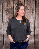 The Ellis Top in black being styled and modeled on women in front of wood background.