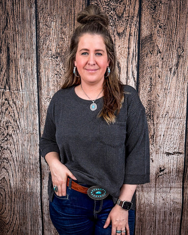 The Ellis Top in black being styled and modeled on women in front of wood background.