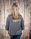 The Ellis Top in black being styled and modeled on women in front of wood background.