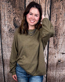 The Stillwater Tunic Top in Olive being styled and modeled on women in front of wooden backdrop.
