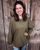 The Stillwater Tunic Top in Olive being styled and modeled on women in front of wooden backdrop.
