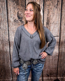 The Hadley Top in Charcoal being styled with jeans and worn by a women in front of wood background.