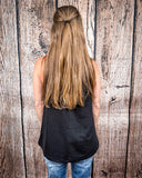 The Lanie Tank in black being styled and modeled by a women in front of wood background.