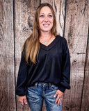 The Hadley Top in black styled and modeled on women in front of wood background.